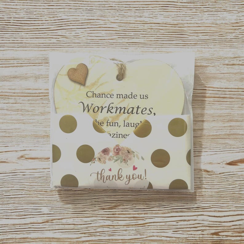Puede incluir: Placa de madera en forma de coraz&oacute;n con el texto "Chance made us Workmates" y un peque&ntilde;o coraz&oacute;n de madera. Se empaqueta con una tarjeta de lunares blancos y dorados que dice "thank you!" con un dise&ntilde;o floral.
