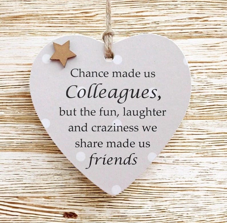 Puede incluir: Placa de madera en forma de coraz&oacute;n con el texto "Chance made us Colleagues, but the fun, laughter and craziness we share made us friends." Con una peque&ntilde;a estrella de madera y cuerda.