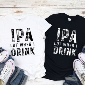 Pode incluir: Duas camisetas com uma estampa gráfica desbotada que diz "IPA Lot When I Drink". Uma camiseta é branca e a outra é preta.
