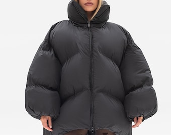 May include: An oversized black puffer jacket with a high collar and a full-length front zipper. The jacket features a quilted design with large, rounded horizontal baffles. It is paired with sheer black tights featuring a repeating heart pattern.
