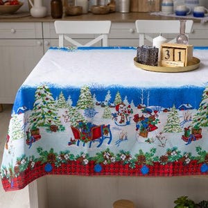 May include: A rectangular tablecloth featuring a winter scene with snowmen, a red sleigh, and evergreen trees on a white and blue background. The bottom border displays a red and black buffalo plaid pattern with pinecones and cotton bolls.