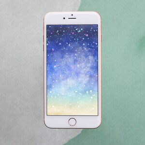May include: A white smartphone with a rose gold frame displays a watercolor background with a galaxy design. The background is a gradient of blue, light blue, and yellow with white stars and glitter.