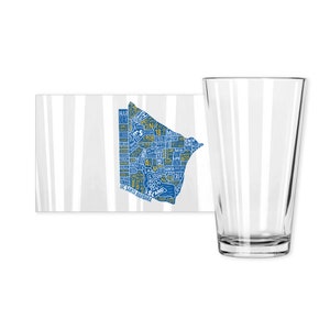 May include: A clear glass pint glass next to a white and gray striped coaster. The coaster features a blue and yellow map design with the text "UC SANTA BARBARA".