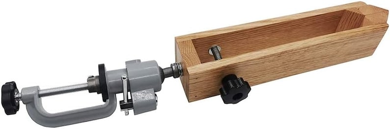 K&ouml;nnte beinhalten: Eine Holzklemmzange mit einer daran befestigten Metallklemmzange. Die Holzklemmzange hat einen Knopf an der Seite und die Metallklemmzange eine Schraube an der Seite. Die Klemmzange dient dazu, ein St&uuml;ck Holz festzuhalten.