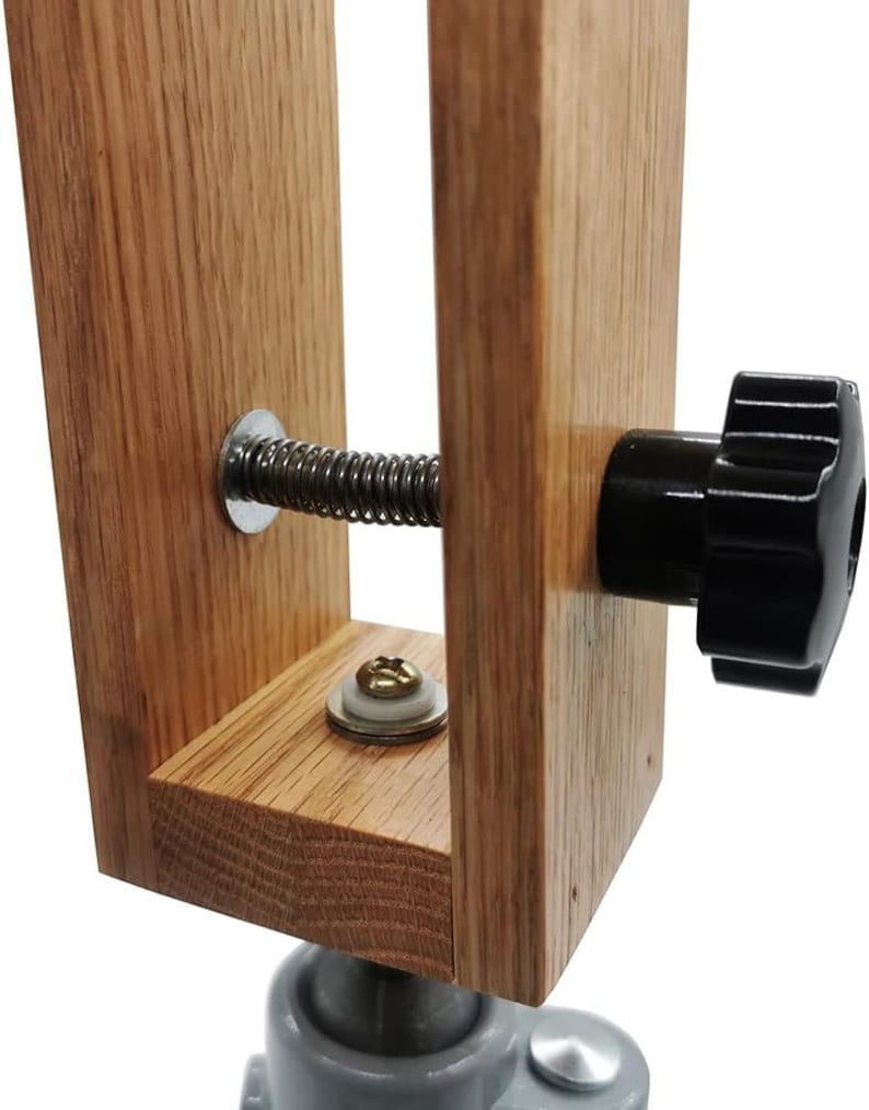 K&ouml;nnte beinhalten: Nahaufnahme eines Holzschuhspanners mit einer Feder und einem schwarzen Knopf. Der Schuhspanner ist aus hellbraunem Holz und hat eine Metallbasis.