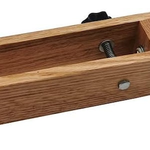 K&ouml;nnte beinhalten: Eine Holzklemmzange mit einer grauen Metallklemme und einem Knopf. Die Holzklemmzange hat eine Nut zum Halten eines Objekts.