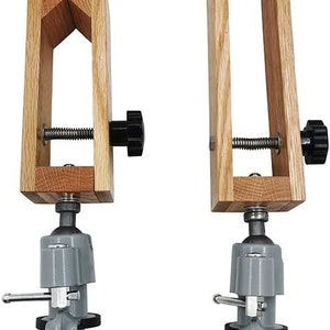 K&ouml;nnte beinhalten: Zwei Holz-Zwingen mit verstellbaren Spannkn&ouml;pfen und grauen Metallsockeln. Die Zwingen sind auf einem wei&szlig;en Hintergrund montiert.