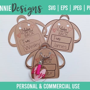 May include: Three brown paper Valentine's Day cards shaped like backpacks with the text "Valentine I Got Your Back" and a space to write "From:" and a name. The bottom card has a clear circle with a pink tassel and the name "Kya" written inside.