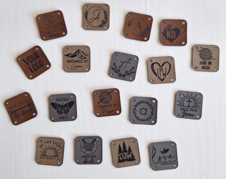 K&ouml;nnte beinhalten: Eine Sammlung von 16 quadratischen Leder-Etiketten mit verschiedenen Designs und Texten. Die Etiketten sind braun, grau und schwarz. Einige der Texte beinhalten "Your Logo", "Handmade by Gwen", "Made with Grace", "Love Never Fails" und "Knit by Alecia".