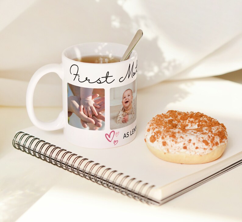 Pu&ograve; includere: Una tazza in ceramica bianca con la scritta nera "First Mother as long as I live" e due foto di un bambino. La tazza &egrave; piena di t&egrave; e un cucchiaio d'argento &egrave; appoggiato sul bordo. Un donut &egrave; appoggiato su un quaderno bianco con una rilegatura a spirale.