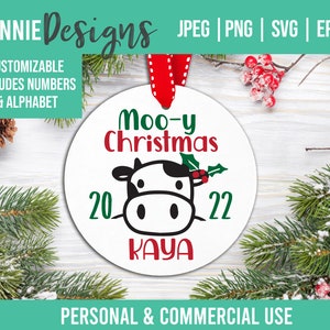 Peut inclure: Une boule de Noël ronde blanche avec une illustration de vache noire et blanche, du houx vert et des baies rouges. Le texte "Moo-y Christmas 20 22 Kaya" est imprimé sur la boule.