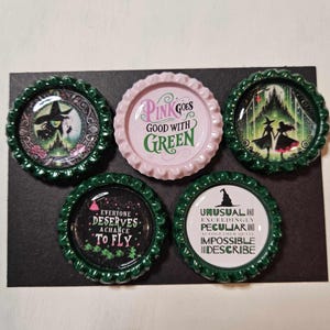 May include: Set of five green and pink bottle cap magnets with quotes from the movie "Wicked". The quotes are: "Pink goes good with green", "Everyone deserves a chance to fly", "Unusual and exceedingly peculiar and altogether quite impossible to describe", and two images of the Wicked Witch of the West.