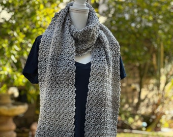 May include: A gray and white ombre crochet scarf with fringe on the ends. The scarf is displayed on a white mannequin.