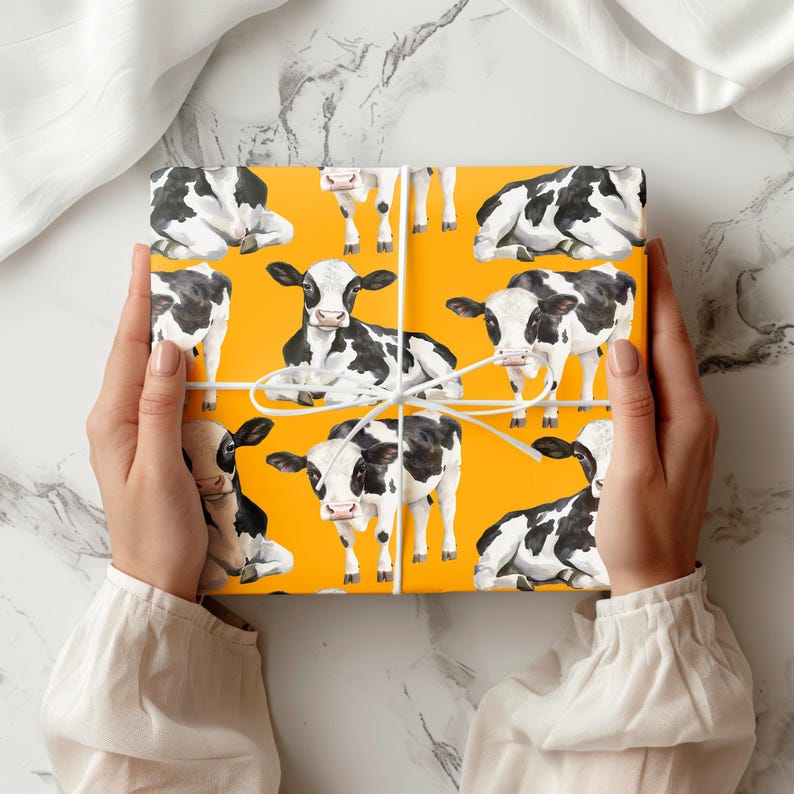 May include: Gift wrap featuring a repeating pattern of black and white cows on a bright yellow background. The cows are in various poses. The gift wrap is tied with white string.