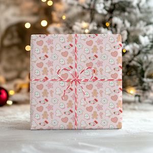 May include: A wrapped present featuring a Christmas pattern. The wrapping paper is light pink and decorated with gingerbread men, candy canes, mittens, stars, hearts, and Christmas trees. The gift is tied with red and white twine.