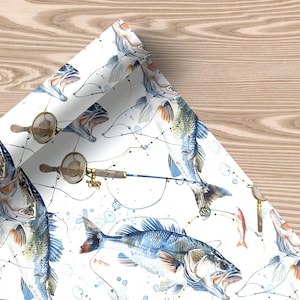 Wrapping paper featuring jumping bass fish, fishing rods, reels, and lures on a white background, unrolled with soft decor and a plush toy.