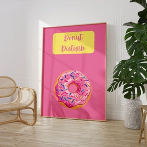 May include: Pink and yellow poster with the text "Donut Disturb" and a pink donut with colorful sprinkles on a pink background.