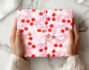 May include: Pink wrapping paper with a repeating pattern of red cherries and white flowers with pink bows.