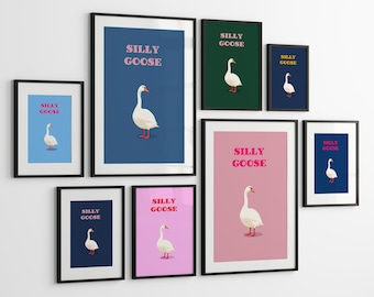 May include: A gallery wall arrangement of eight framed art prints, each featuring a white goose illustration and the text SILLY GOOSE in various colors against solid backgrounds of blue, dark green, navy, and pink, all in black frames.