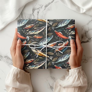 Könnte beinhalten: Ein verpacktes Geschenk mit einem dunklen Hintergrund und einem sich wiederholenden Muster aus bunten Fischen und Angelködern. Das Geschenk ist mit weißem Bindfaden gebunden. Das Thema ist Angeln.