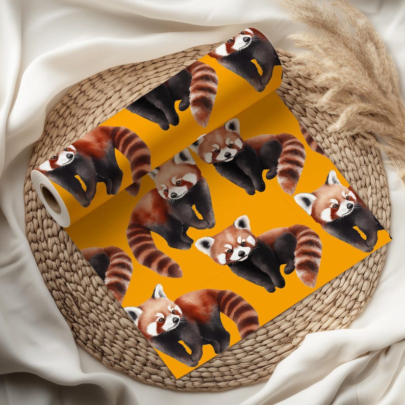 K&ouml;nnte beinhalten: Eine Rolle gelbe Tapete mit einem sich wiederholenden Muster von roten Pandas. Die roten Pandas haben braunes und schwarzes Fell mit gestreiften Schw&auml;nzen. Die Tapete wird auf einem Weidenkorb pr&auml;sentiert.