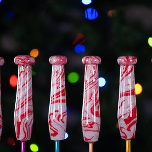 May include: Set of six red and white candy cane swirl knitting needles. The needles are made of wood and have a smooth finish.