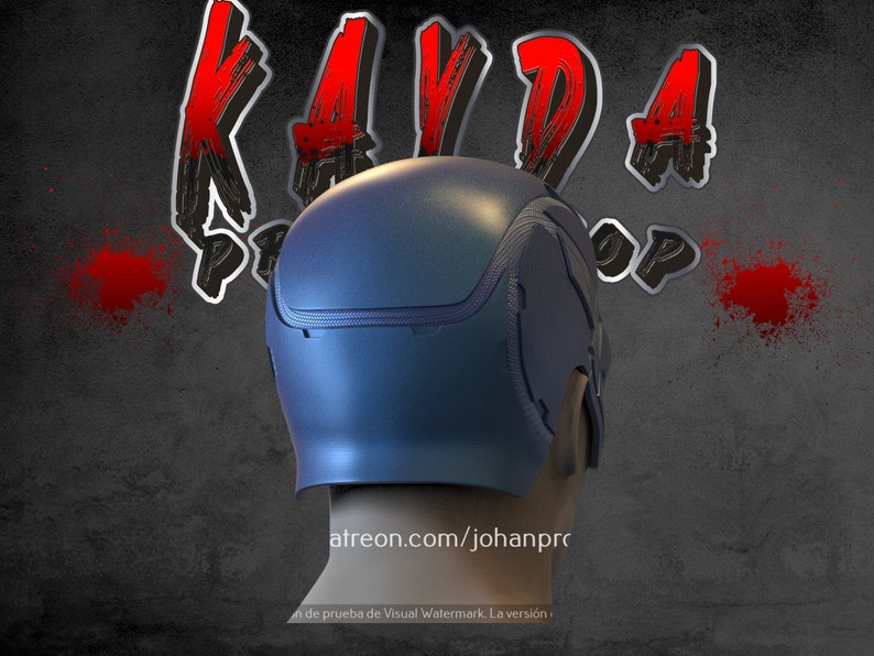 Op de afbeelding: Een blauwe helm met een textuur en een ritsdetail. De helm staat op een grijze achtergrond met rode verfspatten.