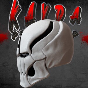 Op de afbeelding: Een wit en zwart 3D-geprint schedelmasker met een scherp, hoekig ontwerp. Het masker heeft een gedetailleerd, getextureerd oppervlak en een dreigende uitdrukking.