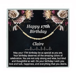 May include: A gold necklace with beads and a small charm that says "Claire". The necklace is in a black box with a floral design and the text "Happy 17th Birthday".