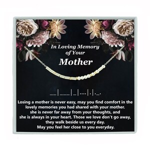 May include: A silver necklace with gold beads and a black box with a floral design. The box has the text "In Loving Memory of Your Mother" and a message about finding comfort in memories.