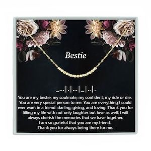 May include: A gold necklace with a beaded chain and a charm that says "Bestie" in a black box with a floral design and a message about friendship. The message reads: "You are my bestie, my soulmate, my confident, my ride or die. You are very special person to me. You are everything I could ever want in a friend: darling, giving, and loving. Thank you for filling my life with not only laughter but love as well. I will always cherish the memories that we have together. I am so grateful that you are my friend. Thank you for always being there for me."