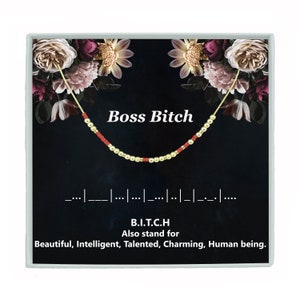 May include: A gold and red beaded necklace with the text "Boss Bitch" and the acronym "B.I.T.C.H." which stands for "Beautiful, Intelligent, Talented, Charming, Human being."