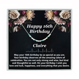 May include: A silver necklace with blue and white beads in a black box with a floral design. The box has the text "Happy 16th Birthday" and "Claire" on it. The text reads: "May your 16th birthday be as special as you are. Your birthday deserves all the amazing colors of celebration. You are not only strong and wise, but kind and thoughtful as well. On your birthday I wish you love and luck, happiness, and everything that you desire."