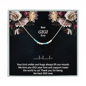 May include: A silver necklace with turquoise beads and a black card with the text "Best GIGI Ever" and a floral design.