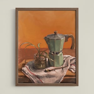 Peut inclure: Peinture encadrée de nature morte avec une cafetière italienne verte à manche en bois, un petit pot en verre avec une plante et une cuillère dorée. Les objets sont sur un tissu blanc à rayures rouges, sur fond orange.