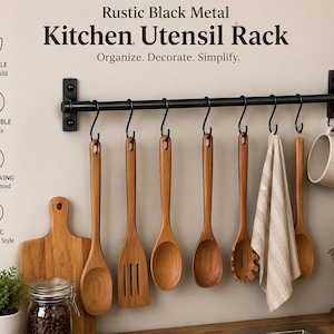May include: A black metal kitchen utensil rack with wooden spoons, a cutting board, and a mug. The rack has removable hooks and is wall-mounted. The image text reads "Organize. Decorate. Simplify."