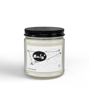 Puede incluir: Una vela en tarro de cristal transparente con tapa negra. La etiqueta presenta un diseño abstracto en blanco y negro con el texto "#@!%" y "YOUR NAME". La vela está rellena de cera blanca cremosa.