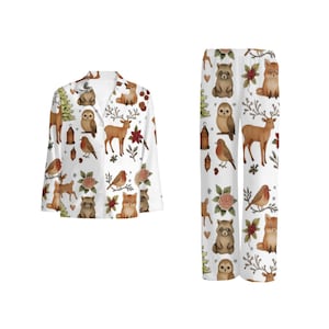 May include: White pajama set featuring a woodland animal print. The set includes a button-down shirt and trousers, both decorated with deer, foxes, owls, raccoons, birds, and floral accents. The pajama set is designed for comfort and style.