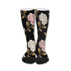 May include: A pair of knee-high socks with a black background and a floral pattern. The design features pink and white roses with gold-colored leaves and stems. The socks have black toes and white tops.