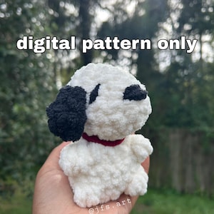 May include: A white and black crochet dog with a red collar. The plush toy has black ears and eye patches. The text "digital pattern only" is displayed at the top of the image. The artist's name, "jfs.art", is displayed at the bottom.