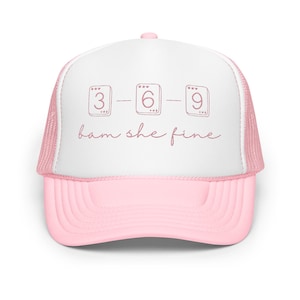 May include: A pink and white trucker hat with the text "3-6-9 bam she fine" in a handwritten style. The hat has a pink brim and a white front panel with a pink mesh back.