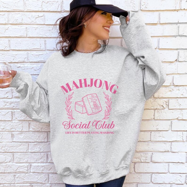 May include: Gray sweatshirt with a pink graphic design that says "Mahjong Social Club" and "Life is better playing Mahjong".