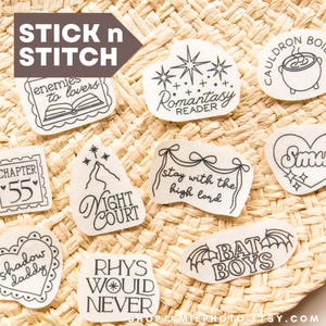 May include: A collection of white adhesive embroidery stabiliser patches featuring black line art designs and text including "enemies to lovers," "Romantasy Reader," "Cauldron Boil Me," "Chapter 55," "Night Court," "stay with the high lord," "Smut," "shadow daddy," "Rhys Would Never," and "Bat Boys."