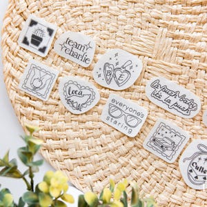 May include: A collection of ten individual white stickers with black line art designs, including text such as team charlie, la push baby it's la push, everyone's staring, and cullen, alongside illustrations of a cactus, wolf, locket, car, and trees.