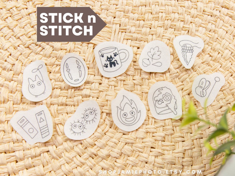 May include: A set of ten iron-on patches featuring characters and objects from the popular animated film, "My Neighbor Totoro." The patches are white with black outlines and are arranged on a woven straw background. The text "STICK n STITCH" is visible at the top of the image.