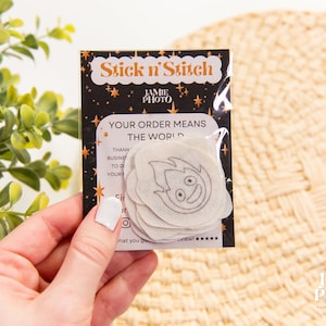 May include: A package of white fabric patches with a black and gold design. The package says "Stick n' Stitch" and "Your order means the world".