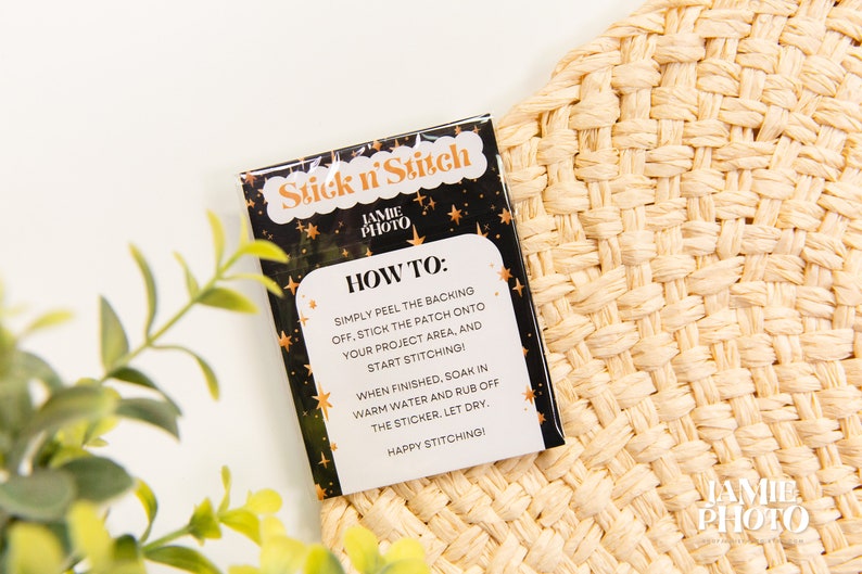 May include: A black and gold card with the text "Stick n' Stitch" and instructions on how to use the product. The card is on a woven straw surface.