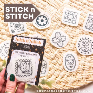 May include: A collection of Stick n' Stitch embroidery patches with various black and white designs, including flowers, geometric shapes, and a bunny. The patches are displayed on a woven surface, with a card that reads "Your order means the world."