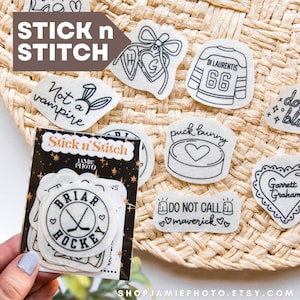 May include: A collection of white adhesive embroidery stabilizer patches featuring black line art designs including hockey jerseys, hearts, and text phrases like Not a vampire, puck bunny, and Do not call maverick, packaged in a branded Stick n Stitch sleeve.