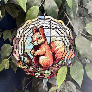 May include: A stained glass style metal wind spinner featuring a red squirrel with a bushy tail. The squirrel is sitting on a branch with leaves. The wind spinner is designed to spin in the wind.